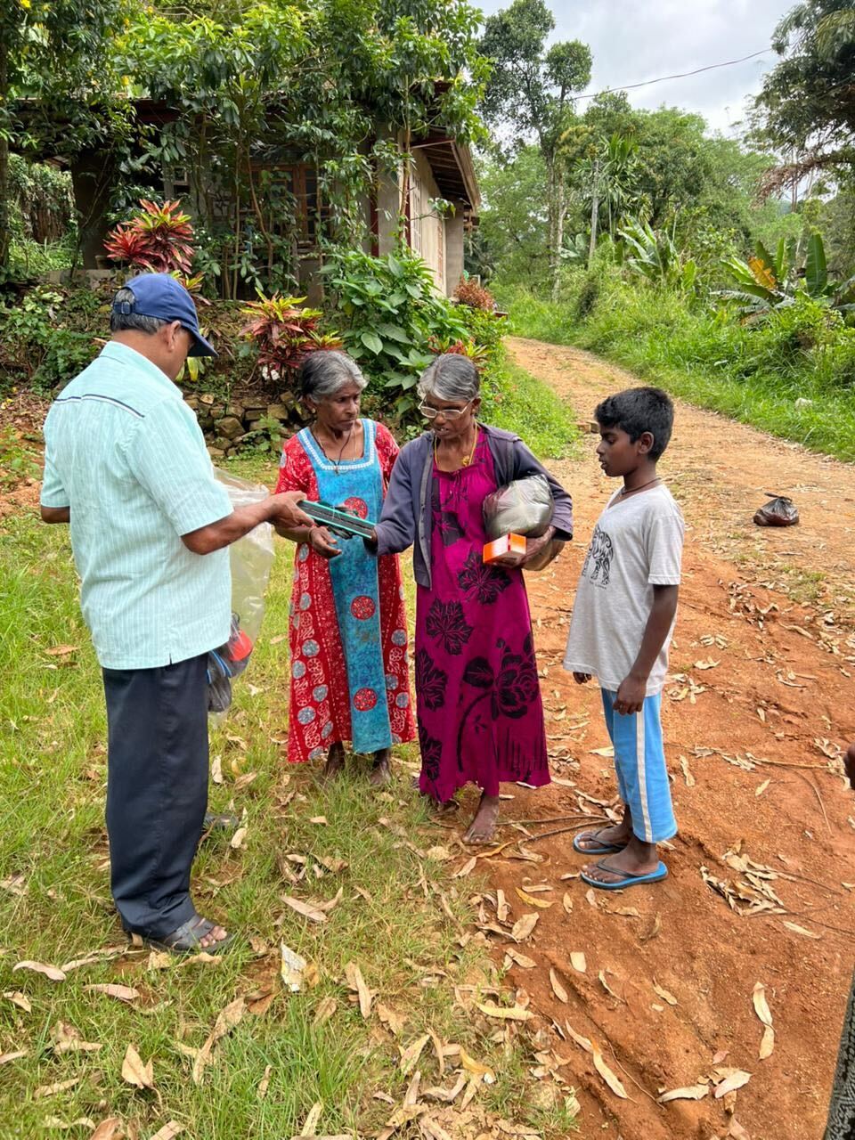 A man hands relief supplies to a family in a rural Sri Lankan jungle village.