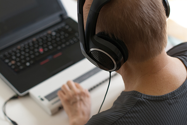 Visually impaired working on computer with assistive technology; braille display and screen reader.