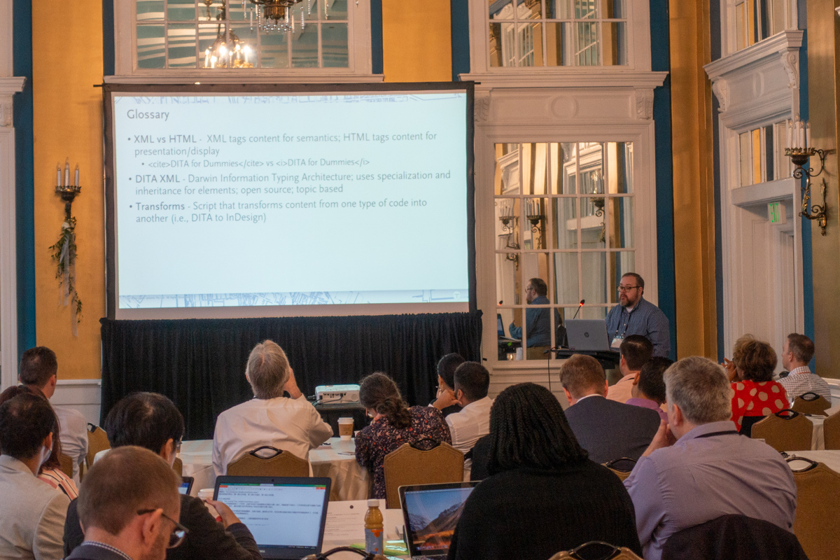 Peyton Bentley presenting at the 2019 Typefi User Conference. The screen shows a glossary of terms from his presentation, including XML vs HTML, DITA XML, and Transforms.