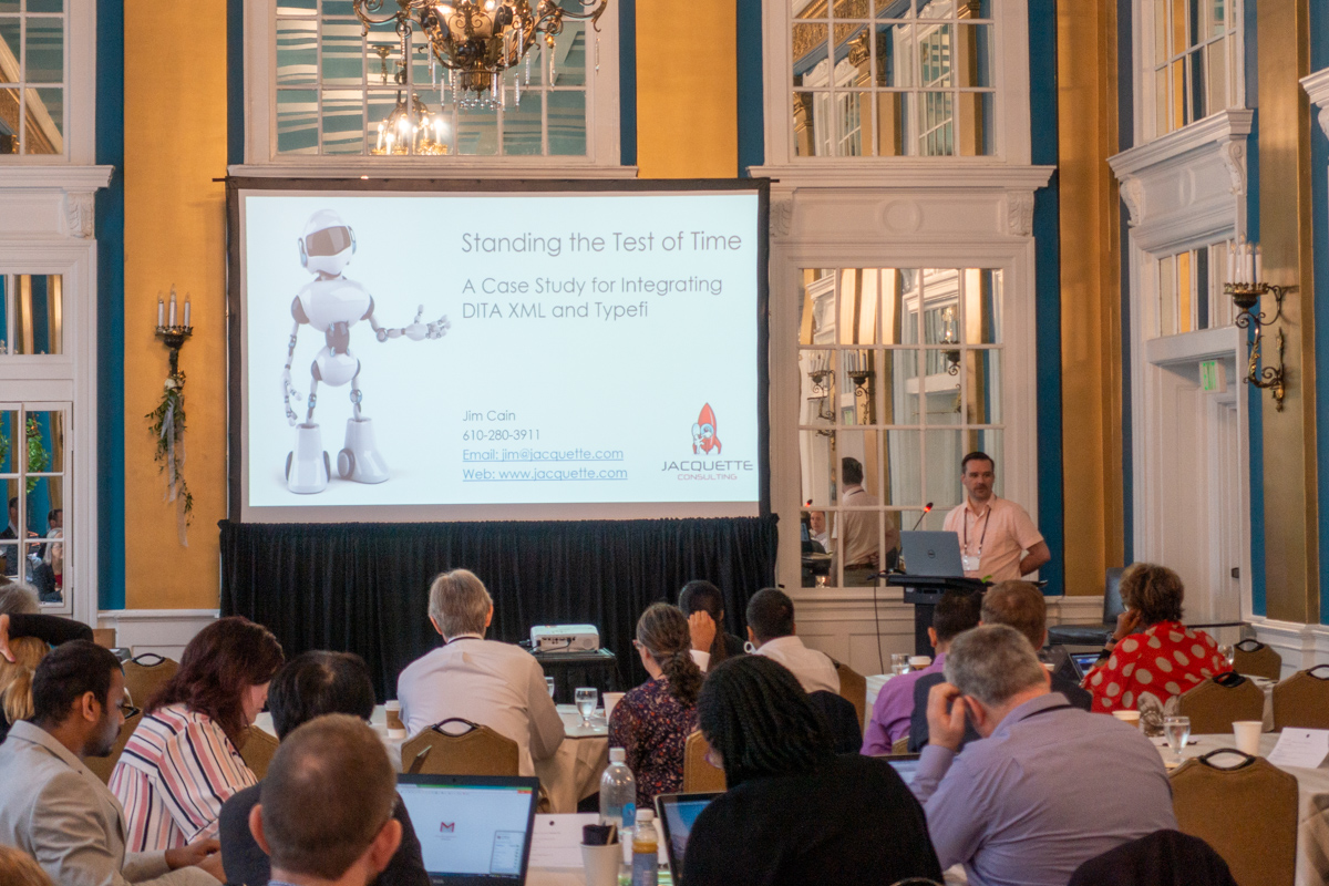 Jim Cain presenting at the 2019 Typefi User Conference. On the screen is an image of a robot, and the title 'Standing the Test of Time: A Case Study for Integrating DITA XML and Typefi'.