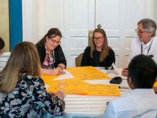 A group of guests writes product ideas on large yellow post-it notes.