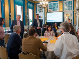 A group of Typefi staff members and customers around a table finalising their ideas on large yellow post-it notes.