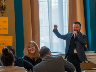 Karl Jankowski enthusiastically presents his group's product feature ideas while Emily Johnston laughs (with him, not at him)!