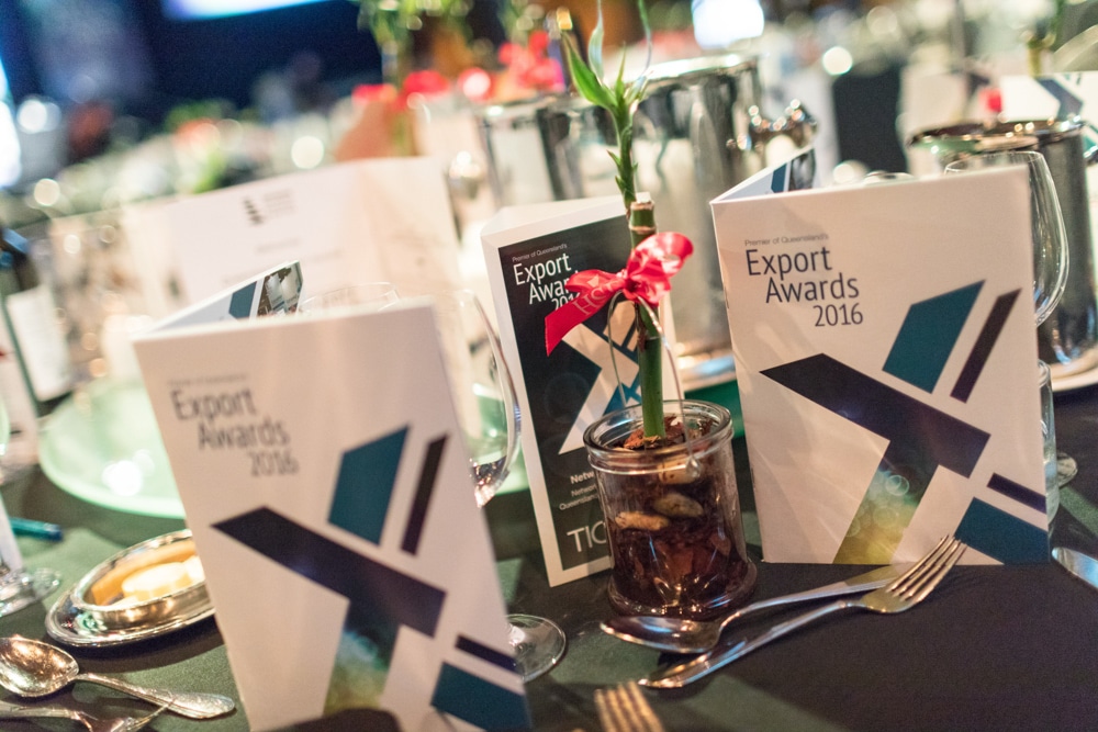 A table set for the 2016 Premier of Queensland's Export Awards with cutlery, awards programs, and bamboo table decorations.