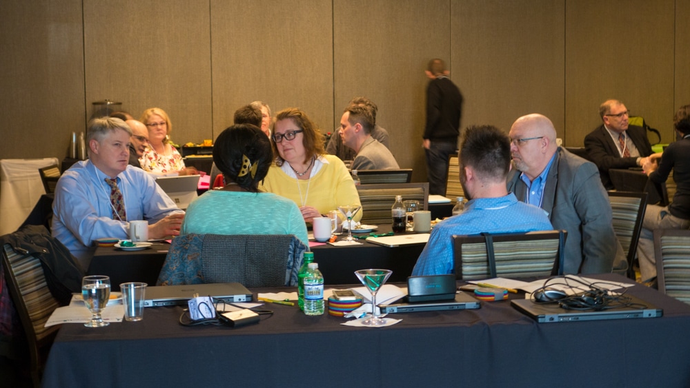 Two groups of Typefi staff and customers sit around tables discussing products and features at the 2017 Typefi User Conference.