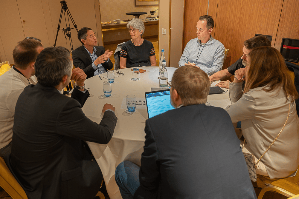Guy van der Kolk hosting a round table discussion at the 2022 Typefi User Conference. There is a group of people sitting at a round table having a conversation.
