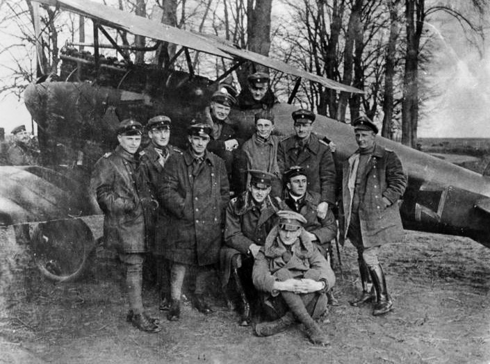 Red Baron Richthofen sits in his WW1 Fokker fighter surrounded by his Flying Circus air squadron.