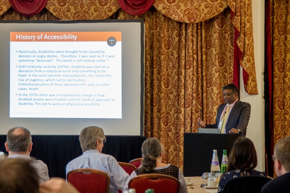Typefi CEO Chandi Perera presenting at the Accessible Publishing workshop. A slide on the history of accessibility is displayed on a projector screen.
