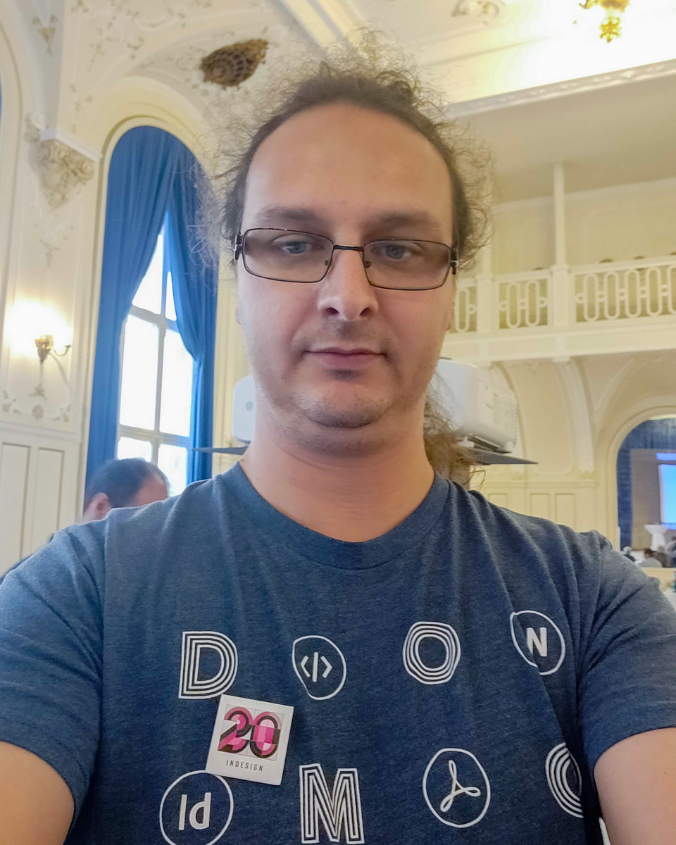Selfie of Vlad Vladila wearing a Typefi shirt that says DO MORE. He has a small badge with with Adobe's official '20 years of InDesign' artwork.