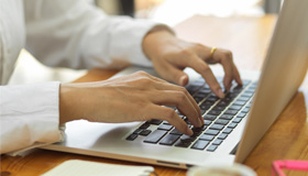 Female hands typing on the keyboard of a Mac laptop